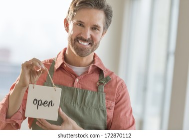 Portrait Of Happy Mature Male Owner Holding Open Signboard