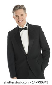 Portrait Of Happy Mature Man In Tuxedo Standing Against White Background