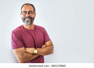 Portrait of happy mature man wearing spectacles and looking at camera indoor. Man with beard and glasses feeling confident.  Handsome mature man posing against a grey background - Powered by Shutterstock