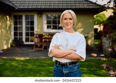 Portrait of happy mature woman standing outside her house.  - Powered by Shutterstock