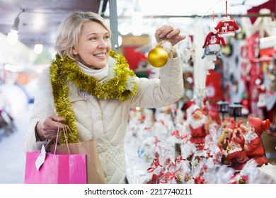 Portrait Of Happy Mature Woman In Tinsel With Christmas Toys At Fair Outdoor.