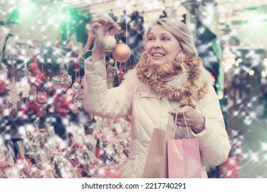 Portrait Of Happy Mature Woman In Tinsel With Christmas Toys At Fair Outdoor.