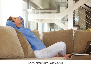 Portrait Of Happy Middle Age Woman Sitting On Sofa With Laptop