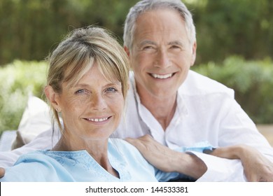 Portrait Of Happy Middle Aged Couple Relaxing In Garden