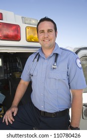 Portrait Of A Happy Middle Aged EMT Doctor Standing With Ambulance In The Background