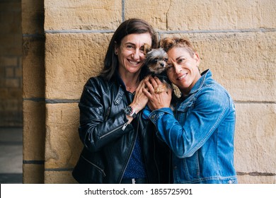 Portrait of a happy middle aged lesbian couple hugging their yorkshire terrier  - Powered by Shutterstock