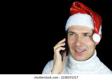 Portrait of happy middle aged man in Santa hat talking on mobile phone on black background. Christmas greetings, New Year holiday - Powered by Shutterstock