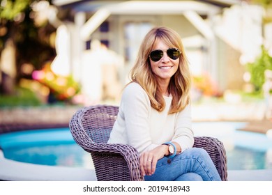 Portrait Of Happy Middle Aged Woman Wearing Sunglasses While Relaxing At The Backyard Background With Pool. 