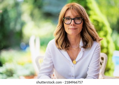 Portrait Of Happy Middle Aged Woman Sitting In A Lounge Chair While Relaxing At The Backyard.