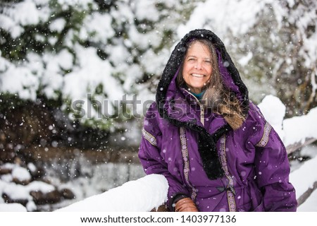 A portrait of a happy middle aged woman wearing a hooded jacket in a wintery Colorado, USA 