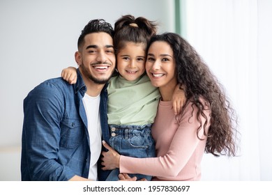 Portrait Of Happy Middle Eastern Family Of Three Posing Together At Home, Loving Young Arab Parents And Their Cute Little Daughter Hugging Near Window And Smiling At Camera, Closeup, Copy Space - Shutterstock ID 1957830697
