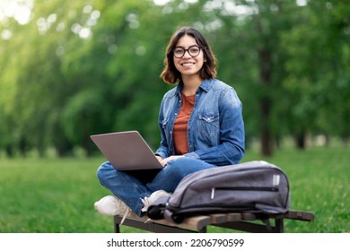 Portrait Of Happy Middle Eastern Female Student Sitting On Bench Outdoors With Laptop, Beautiful Young Arab Woman Using Computer In Park, Enjoying Online Education And Distance Learning, Copy Space - Shutterstock ID 2206790599