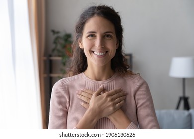 Portrait of happy millennial female volunteer holding folded hands on chest, looking at camera. Kind smiling young woman feeling thankful, showing appreciation, gratitude believe charity concept. - Shutterstock ID 1906130626