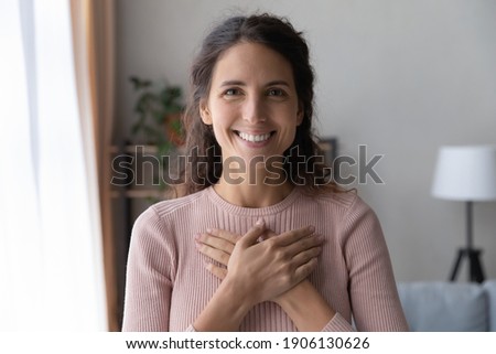 Portrait of happy millennial female volunteer holding folded hands on chest, looking at camera. Kind smiling young woman feeling thankful, showing appreciation, gratitude believe charity concept. Foto stock © 