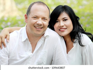 Portrait Of A Happy Mixed Race Couple Outside In The Park