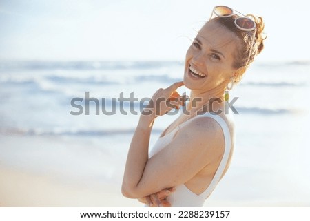Portrait of happy modern middle aged woman in white swimwear at the beach.