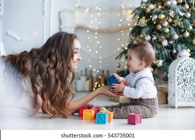 Portrait Of Happy Mother And Adorable Baby Celebrate Christmas. New Year's Holidays. Toddler With Mom In The Festively Decorated Room With Christmas Tree And Decorations.