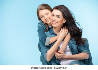 Portrait Of Happy Mother And Daughter Hugging In Studio On Blue