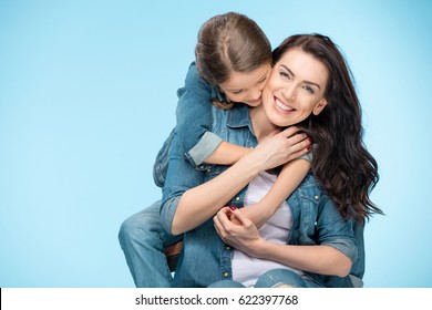 Portrait Of Happy Mother And Daughter Hugging In Studio On Blue