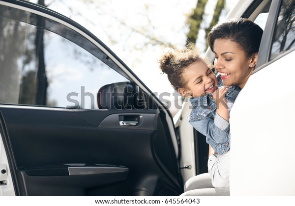 portrait of happy mother and daughter sitting in\
car on parking