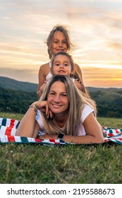 Portrait Of Happy Mother And Daughters Smiling And Laughing Lying On Blanket In Park, They Posing For Photo.