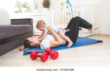 Portrait of happy mother doing exercise at home and having fun with her baby boy