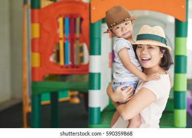 Portrait Of Happy Mother Holding Her Child When Standing On Playground