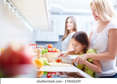 Portrait Of Happy Mother And Two Daughters Cooking In The Kitchen