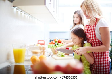 Portrait Of Happy Mother And Two Daughters Cooking In The Kitchen