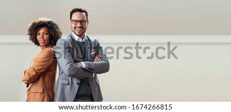 Portrait of happy multi ethnic business couple posing with arms crossed