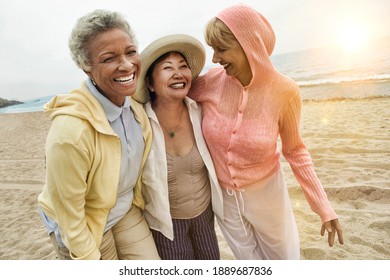 Portrait of happy multi ethnic middle aged female friends enjoying vacation at beach
