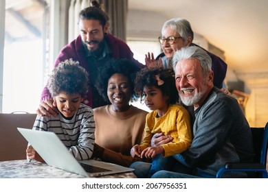 Portrait Of A Happy Multigeneration Family Using Electronic Devices At Home Together