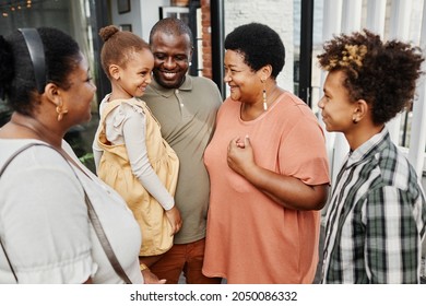 Portrait of happy multi-generational family chatting during gathering outdoors at terrace