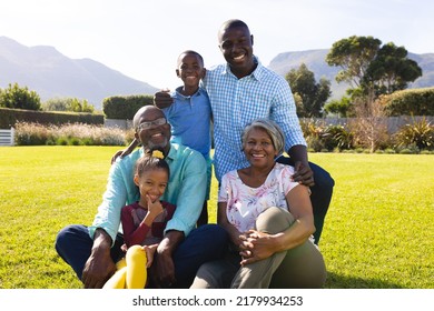 Portrait of happy multiracial multigeneration family enjoying leisure time on grassy field in yard. Summer, copy space, nature, unaltered, togetherness, love, childhood and retirement concept. - Powered by Shutterstock