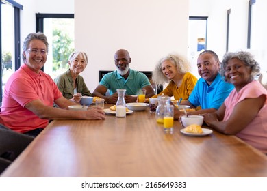 Portrait Of Happy Multiracial Senior Friends With Food And Drink On Dining Table In Nursing Home. Breakfast, Unaltered, Healthy, Togetherness, Support, Assisted Living And Retirement Concept.