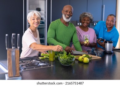 Portrait of happy multiracial senior friends making smoothie with granny smith apple and vegetables. Retirement home, unaltered, togetherness, support, assisted living, kitchen and healthy food. - Powered by Shutterstock