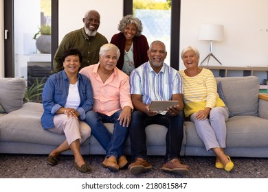 Portrait Of Happy Multiracial Senior Man Holding Digital Tablet Relaxing With Friends On Sofa. Nursing Home, Wireless Technology, Unaltered, Togetherness, Support, Assisted Living, Retirement.