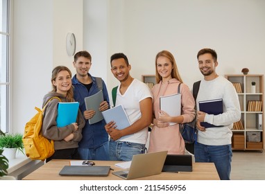 Portrait Of Happy Multiracial Students With Backpacks And Books Pose Together In School Classroom. Group Of Smiling Diverse Young People Learners In College Or University. Education And Courses.