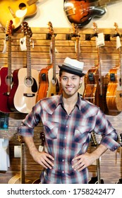 Portrait Of A Happy Music Store Owner Standing In Front Of Guitars