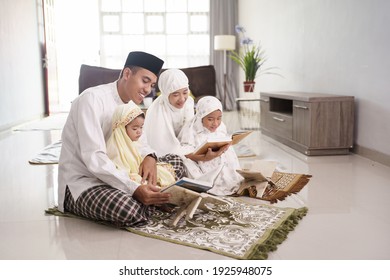 Portrait of happy Muslim family with children reading the Quran and praying together at home.