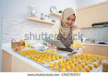 portrait of happy muslim woman with nastar snack in the kitchen
