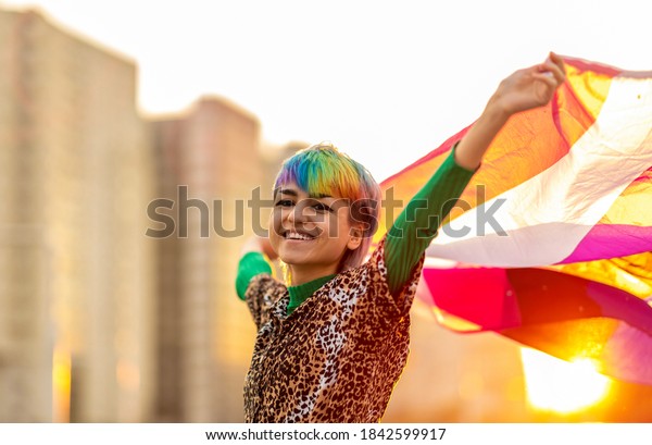 Portrait of happy non-binary person waving\
gender fluid flag\
\
