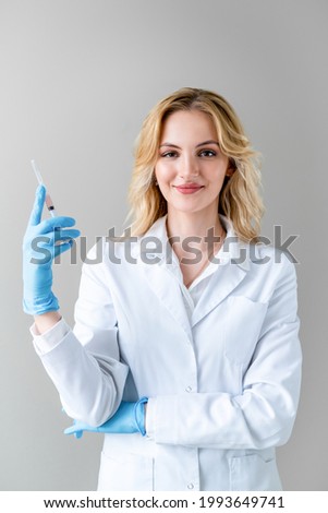Portrait of happy nurse in white coat with vaccine in her hands. Vaccination of population against covid 19. Worldwide pandemic.