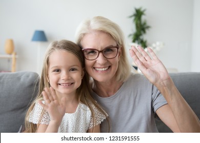 Portrait Of Happy Old Grandmother And Kid Girl Waving Hands Looking At Camera, Smiling Grandma With Granddaughter Making Video Call, Child And Granny Vloggers Recording Video Blog Or Vlog Together