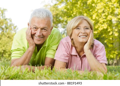 Portrait Of Happy Old People Lying On Green Grass.