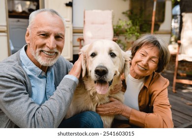 Portrait of happy old senior couple family wife and husband with dog golden retriever, playing and traveling together by camper van, caravanning on trailer motor home - Powered by Shutterstock