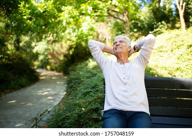 Portrait Happy Older Man Sitting On Park Bench With Hands Behind Head