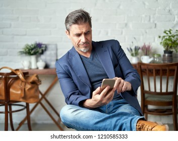 Portrait Of Happy Older White Man With Gray Hair Wearing Jacket Smiling Using Smart Phone. 
 .