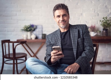 Portrait Of Happy Older White Man With Gray Hair Wearing Jacket Smiling Using Smart Phone. 
 .