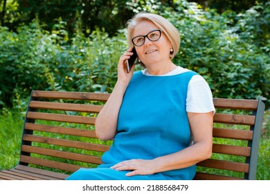 Portrait Happy Older Woman Sitting On Park Bench Talking With Cellphone